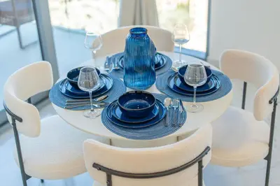 a white table with blue plates and wine glasses at Marcopolo - Signature High-Floor Apartment Facing Burj Khalifa in Sabkhah