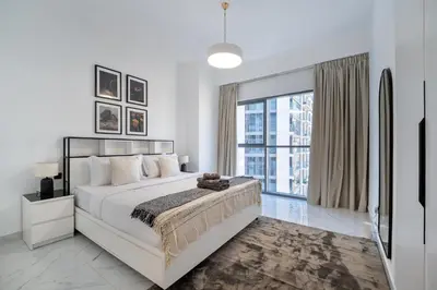 a white bedroom with a large bed and a large window at Marcopolo - Signature High-Floor Apartment Facing Burj Khalifa in Sabkhah