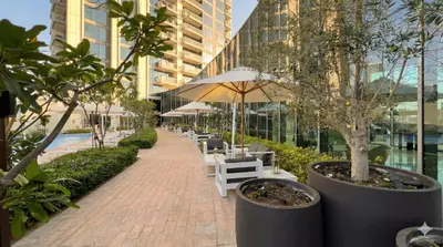 a walkway with white chairs and tables and trees at Emaar 52 42! Iconic Sea-View! Dubai Marina in Dubai