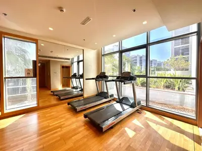 a gym with three treadmills in a room with large windows at Warm & Stylish Studio with Balcony in Dubai