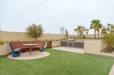 a patio with a table and chairs and grass at Calm & Stylish 1Bedroom in Hadley Heights JVC in Dubai