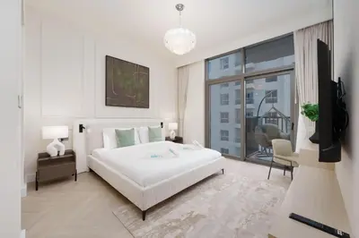 a bedroom with a white bed and a tv in it at Calm & Stylish 1Bedroom in Hadley Heights JVC in Dubai