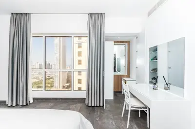 a white bedroom with a desk and a large window at Luxury 2BR Sea View Jumeirah Beach Residence in Dubai
