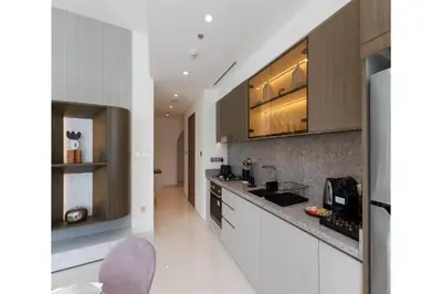 a kitchen with white counters and wooden cabinets at Grand Bleu, Emaar Beachfront - The Mint Stay in Dubai
