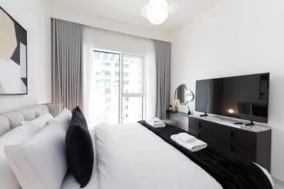 a white bedroom with a large bed and a television at Grand Bleu, Emaar Beachfront - The Mint Stay in Dubai