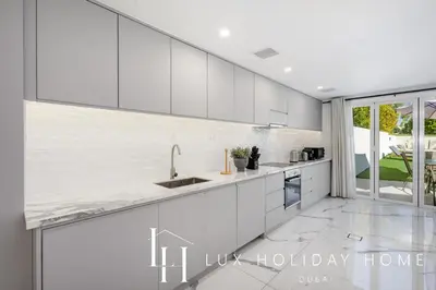 a kitchen with white cabinets and a large window at LUX The Serene Springs Villa 2 in Dubai