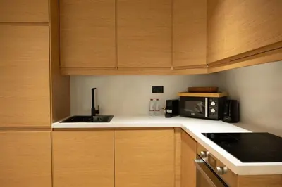 a kitchen with wooden cabinets and a microwave at Stylish cozy studio in the heart of Business Bay in Sabkhah