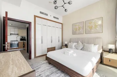 a bedroom with a large white bed and a kitchen at Cozy 1BR Near Metro in Starz Tower 2 in Dubai
