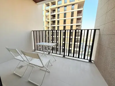 a balcony with two chairs and a table and a building at Cozy & Stylish 1BR in Wilton Terraces in Dubai