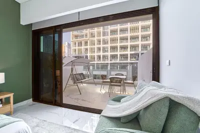 a living room with a couch and a large window at Fresh & Modern Studio in Meydan - Azizi Riviera 67 in Dubai