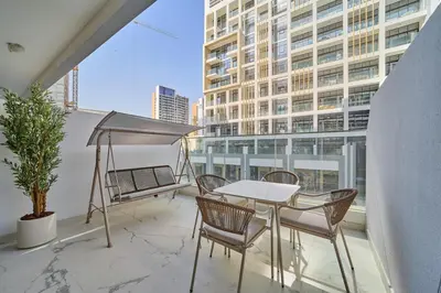 a balcony with a table and chairs and a building at Fresh & Modern Studio in Meydan - Azizi Riviera 67 in Dubai