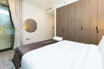 a bedroom with a white bed and a wooden cabinet at Escape24 Brand New 2BR with Canal Views near Burj Khalifa in Dubai