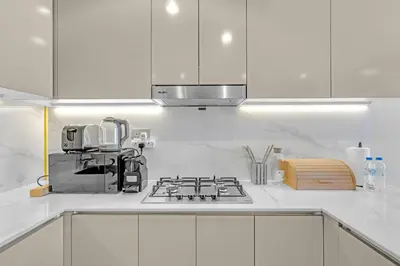 a kitchen with white cabinets and a stove top oven at Stylish 1BR in Great Community in Dubai