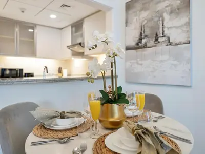 a dining room table with a white table cloth and silverware at Kensington - 1BR Fountain-view Flat Downtown in Dubai