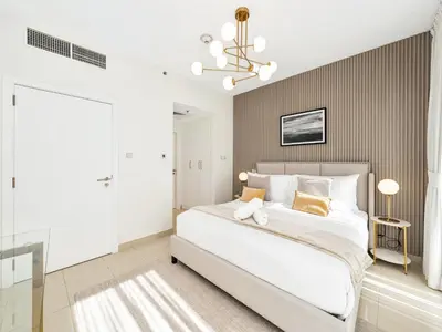 a bedroom with a large white bed and a chandelier at Kensington - 1BR Fountain-view Flat Downtown in Dubai