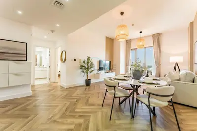a kitchen and living room with a table and chairs at Just Steps from the Community Center with Top-Tier Amenities, Minutes Walk to the Park, Hayat Boulevard 2A, Town Square by Deluxe Holiday Homes in Dubai