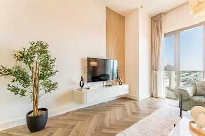 a living room with a tv and a potted plant at Just Steps from the Community Center with Top-Tier Amenities, Minutes Walk to the Park, Hayat Boulevard 2A, Town Square by Deluxe Holiday Homes in Dubai