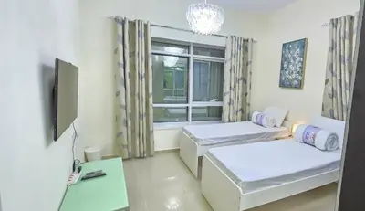 a living room with two beds and a window at Large 2 BHK Apartment Next to DMCC Metro Station in Dubai