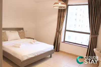 a bedroom with a bed and a large window at Cloud 9 - Steps to the Beach Elegant 2BR in JBR in Dubai