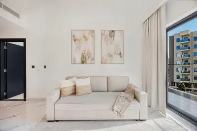 a white living room with a couch and a window at Chic 2BR Haven in Prime Location in Gardenia Living in Dubai