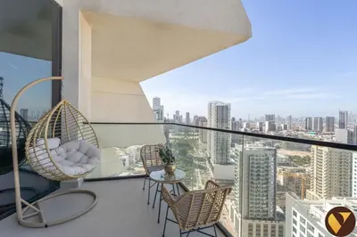 a balcony with wicker chairs and a view of a city at Vogue JVC Binghatti Phantom near Circle Mall, One Bedroom Apartment with Large Balcony and City View, Access to all Amenities in Dubai