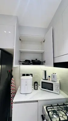 a white kitchen with a stove and a microwave at Kats in Dubai