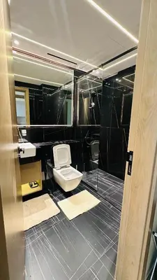 a bathroom with a toilet and black tiled walls at Kats in Dubai