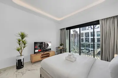 a white bedroom with a bed and a television at Zafir Studio in Dubai by beBalmy in Dubai