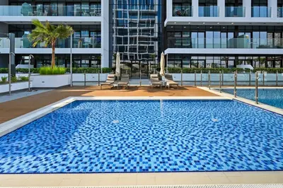 a large swimming pool with two chairs and a building at Zafir Studio in Dubai by beBalmy in Dubai
