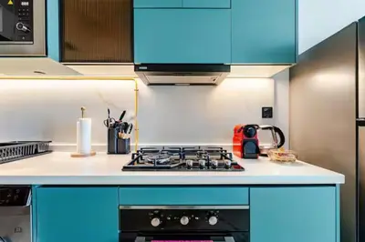 a kitchen with blue cabinets and a stove top oven at Luxury Dubai Studio with Private Pool & Desert Views in Dubai