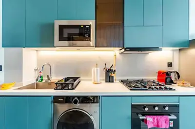 a kitchen with a washing machine and a microwave at Luxury Dubai Studio with Private Pool & Desert Views in Dubai