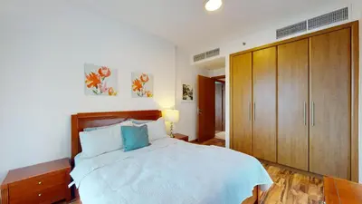 a bedroom with a large bed and wooden cabinets at 2 bedroom JLT with park view in Dubai