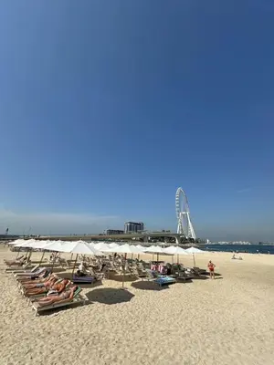 a beach with a bunch of chairs and a white umbrella at Amazing 1BR Address Beach Resort With Private Beach in Dubai