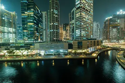 a city skyline at night with a river and buildings at StayMada - Peninsula Exclusive Canal Front Retreat in Dubai