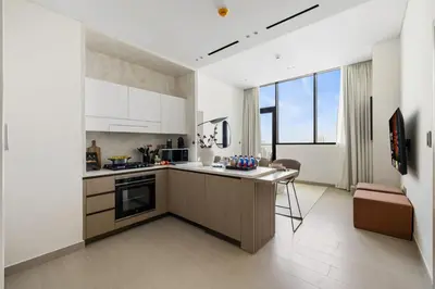 a kitchen with white cabinets and a table in it at New 1BR with Private Pool Near Circle Mall in Dubai