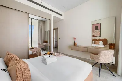 a bedroom with a white bed and a chair at New 1BR with Private Pool Near Circle Mall in Dubai