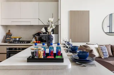 a kitchen with a table with bottles on it at Stylish 1BR with Private Pool Near Circle Mall in Dubai