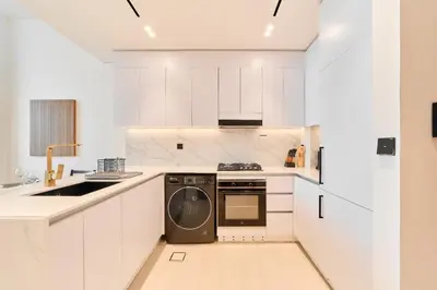 a kitchen with white cabinets and a dishwasher at Cozy 1BR Retreat in Binghatti Amber JVC in Dubai