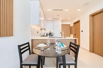 a dining room table with two chairs and a kitchen at Cozy 1BR Retreat in Binghatti Amber JVC in Dubai