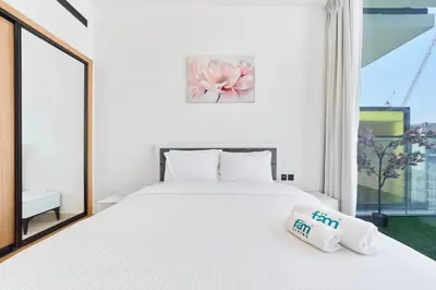 a bedroom with a large white bed and a window at Cozy 1BR Retreat in Binghatti Amber JVC in Dubai