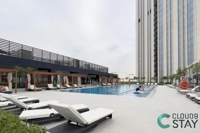 a swimming pool with lounge chairs and a building at Cloud 9 - Townhouse style 2 BR Apt with BBQ Patio in Dubai