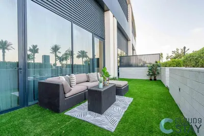 a patio with a couch on the grass on a building at Cloud 9 - Townhouse style 2 BR Apt with BBQ Patio in Dubai