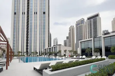 a view of a pool with lounge chairs and buildings at Cloud 9 - Townhouse style 2 BR Apt with BBQ Patio in Dubai