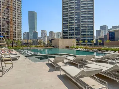a pool with lounge chairs and a city skyline at The Smart Concierge - Peninsula One in Dubai