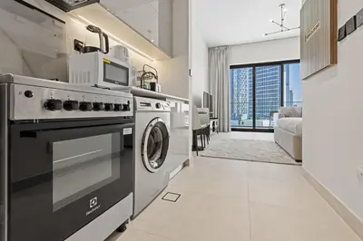 a kitchen with a stove and a washing machine at Cozy City-View Studio w Balcony & Queen Bed in Dubai