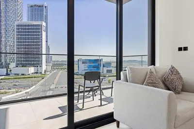 a living room with a view of a city skyline at Cozy City-View Studio w Balcony & Queen Bed in Dubai