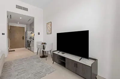 a living room with a flat screen tv on a wall at Cozy City-View Studio w Balcony & Queen Bed in Dubai