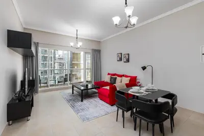 a living room with a red couch and a table at Maison Privee - Comfortable Downtown Apartment with City Skyline Vws in Dubai
