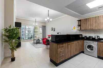 a kitchen with a washing machine and a living room at Maison Privee - Comfortable Downtown Apartment with City Skyline Vws in Dubai