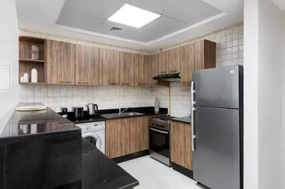 a kitchen with wooden cabinets and a stainless steel refrigerator at Maison Privee - Comfortable Downtown Apartment with City Skyline Vws in Dubai